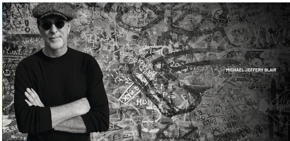 Portrait of Michael Jeffery Blair in front of a graffiti wall.